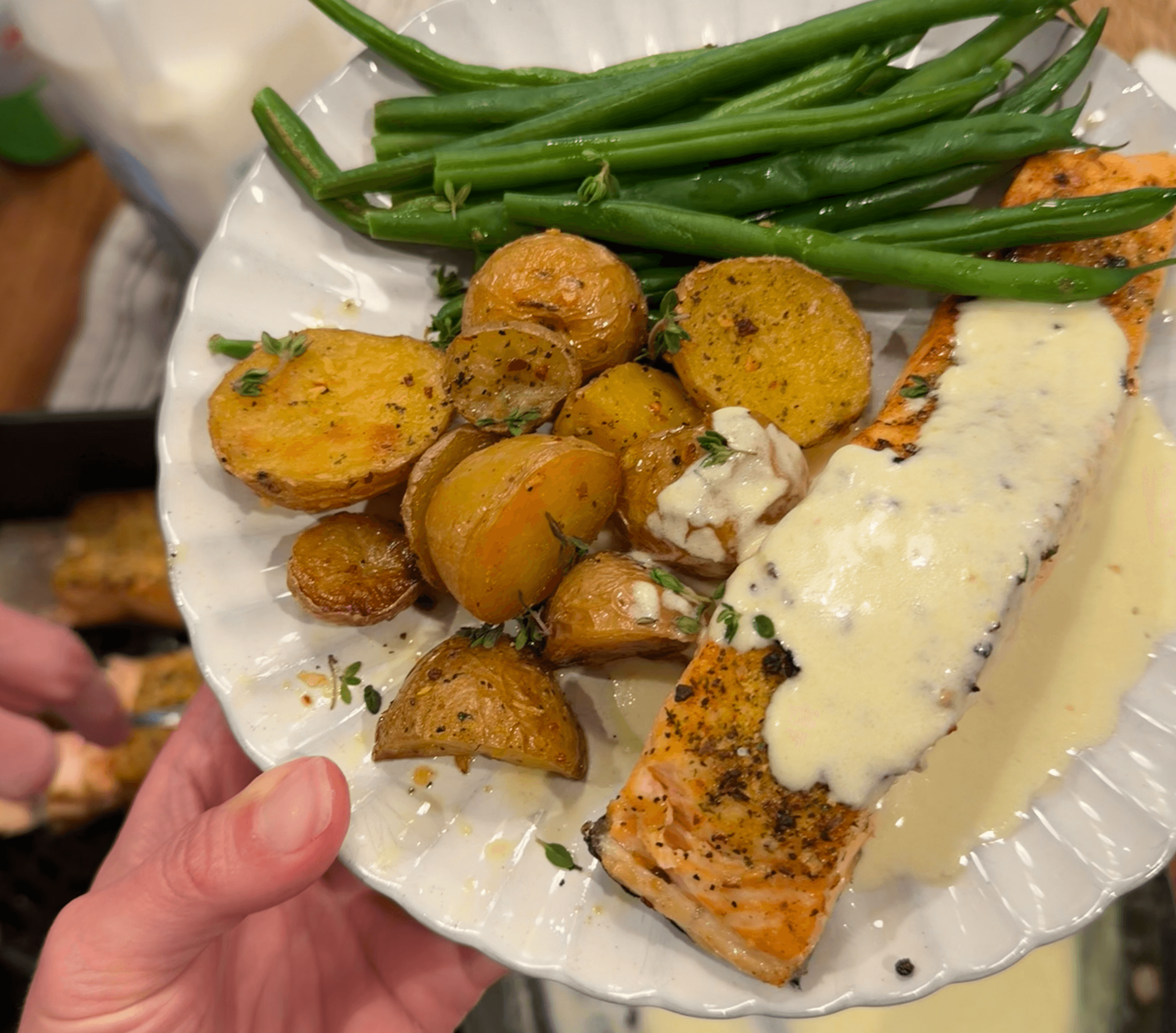 Salmon with lemon sauce, potatoes, and green beans on a plate.