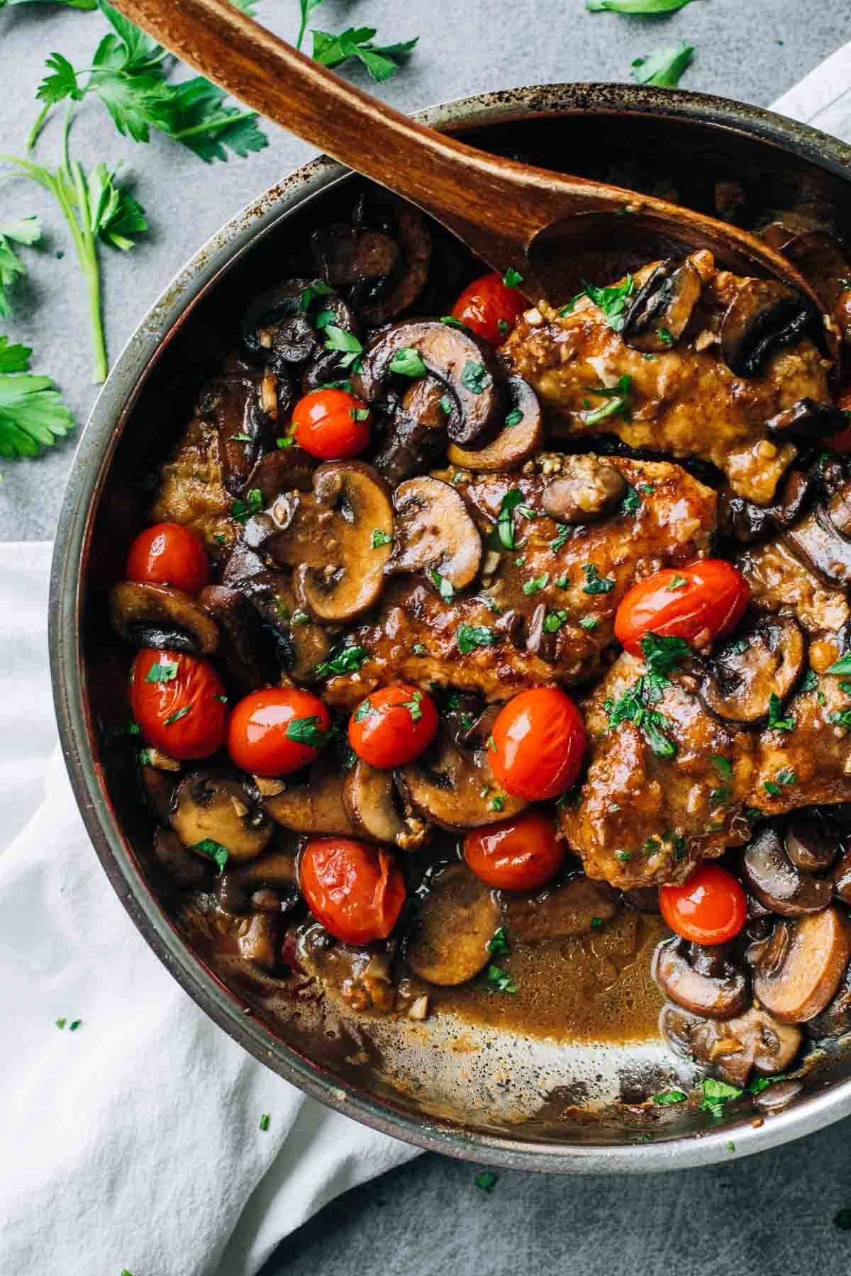 Chicken Marsala in a skillet with a wooden spoon.